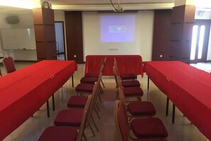 A conference room with a long table, red chairs, and a projector screen. - Zhuhai Xinhong Hotel (Daxin Xinduhui Branch) (Zhuhai)