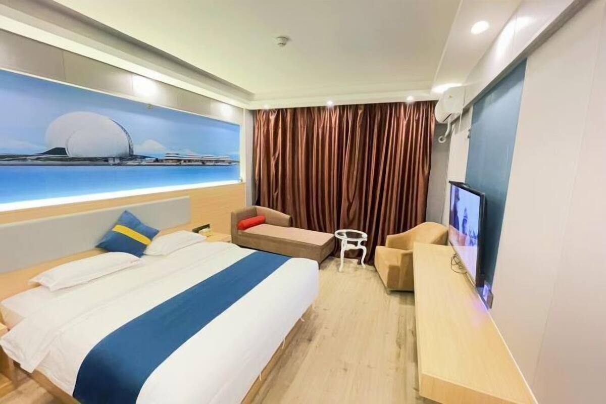 Una habitación de hotel con una cama grande, un escritorio, un televisor y vistas a un puente.