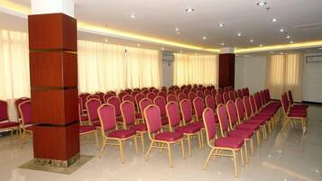 A conference room with rows of chairs, a wooden pillar, and a large window with curtains.