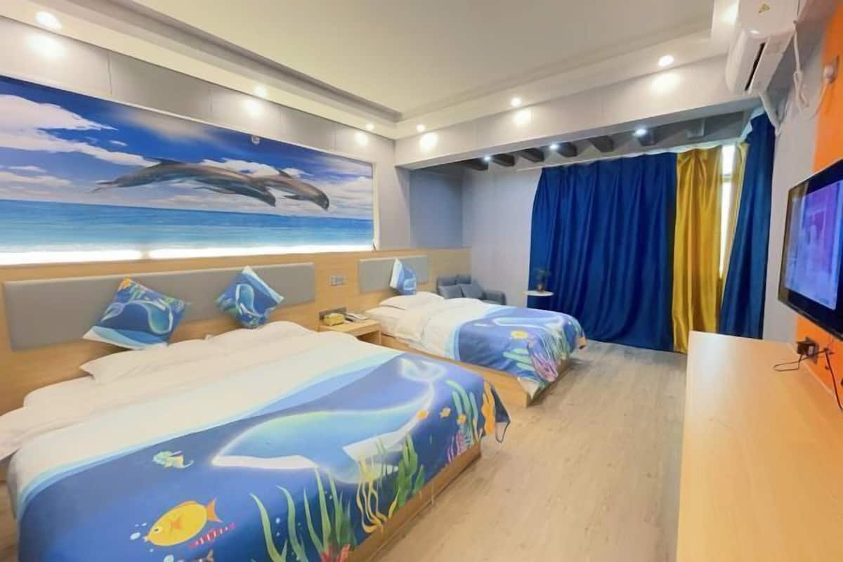 Habitación de hotel con dos camas, un mural grande de un delfín y un televisor a la derecha.