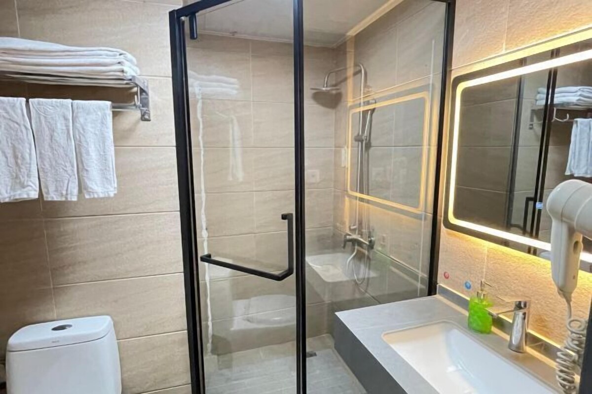 Un baño moderno con ducha de vidrio, lavamanos con espejo y toallero con toallas dobladas.