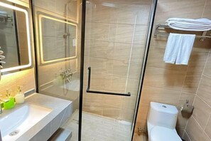 A modern bathroom with a glass shower enclosure, a white sink with a mirror, and a toilet with a towel rack above it. - Zhuhai Xinhong Hotel (Daxin Xinduhui Branch) (Zhuhai)