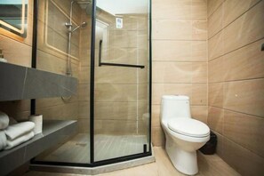 A modern bathroom with a glass-enclosed shower, a toilet, and a vanity with towels. - Zhuhai Xinhong Hotel (Daxin Xinduhui Branch) (Zhuhai)