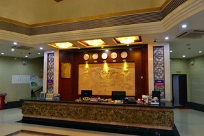 A reception desk with a decorative wall, a clock, and a reception counter. - Zhuhai Xinhong Hotel (Daxin Xinduhui Branch) (Zhuhai)
