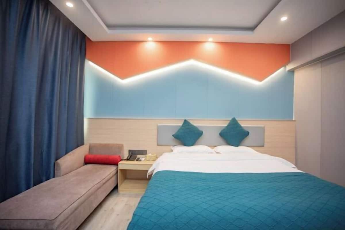 Una habitación de hotel moderna con cama, sofá y mesita de noche.