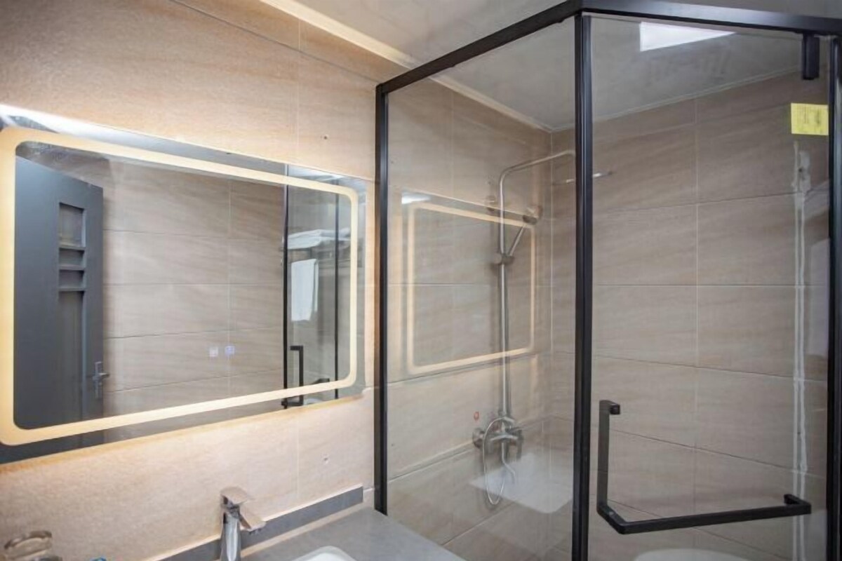 Un baño moderno con cabina de ducha de vidrio, un espejo grande y un lavabo.