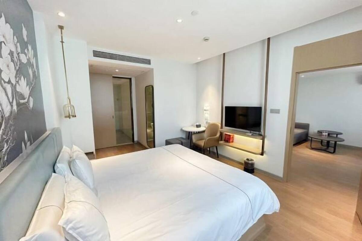 A hotel room with a large bed, a TV, a small table, and a chair.