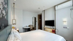 Habitació d'hotel amb llit, televisió, escriptori, cadira i un quadre a la paret.