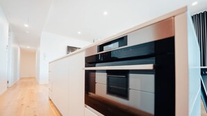 Una cocina moderna con armarios blancos, horno empotrado y encimera de madera.