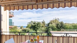 Un balcón con una mesa dispuesta para el desayuno, con vistas a un paisaje con árboles y edificios.