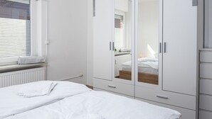 Ein Schlafzimmer mit einem Bett, einem Kleiderschrank und einem Fenster mit Jalousien.