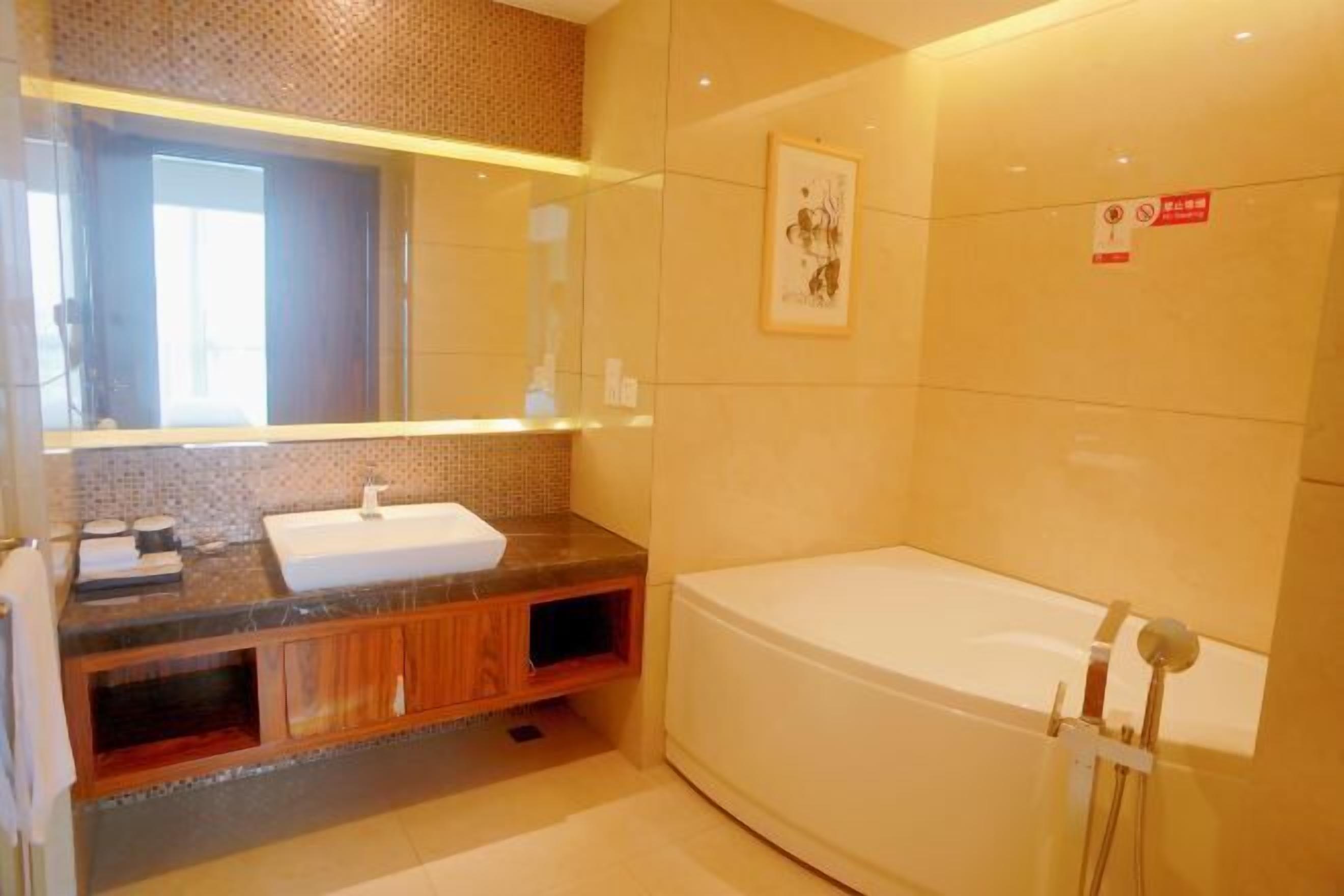 Un baño moderno con un espejo grande, un lavamanos, una bañera y una zona de ducha.
