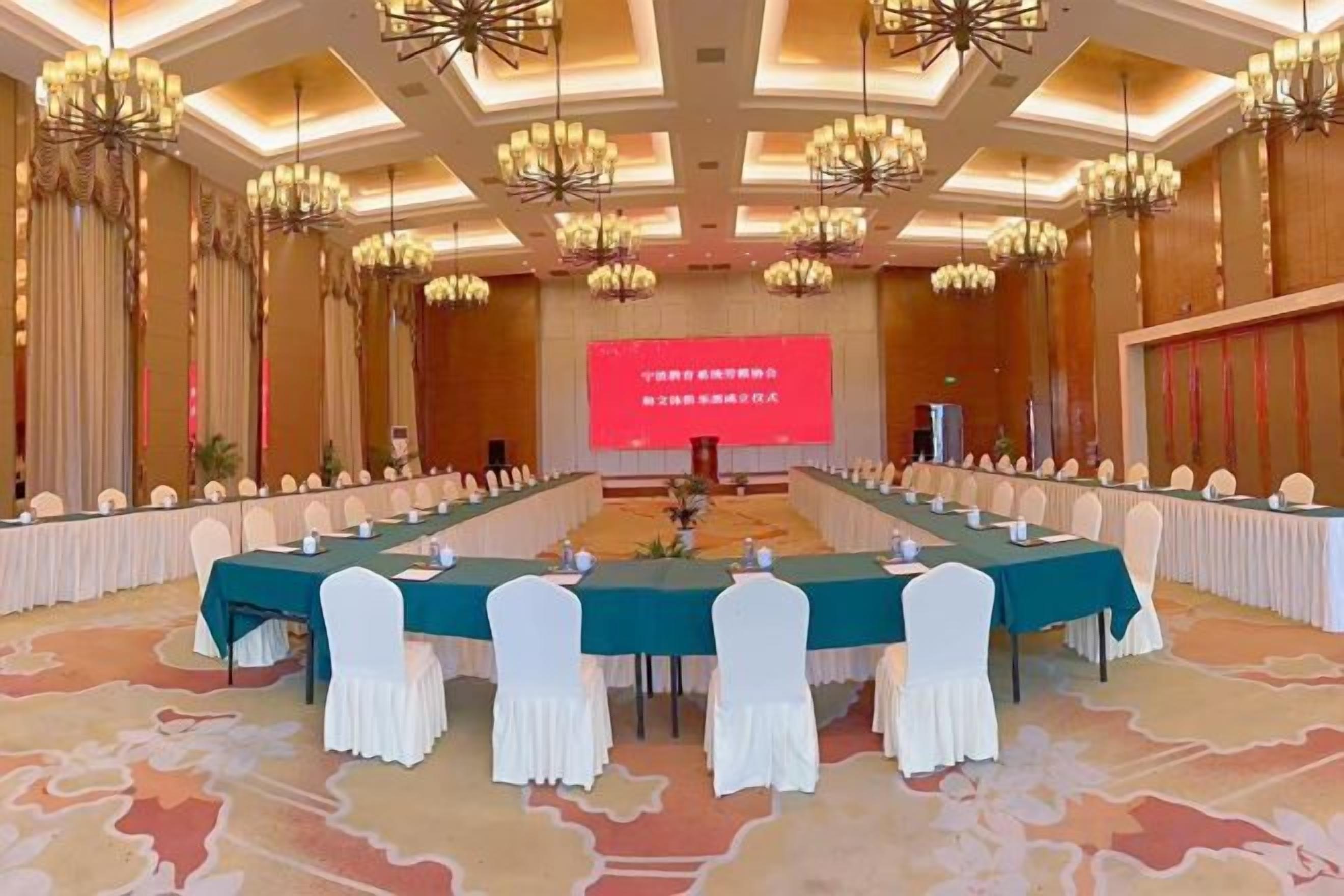 A conference room with a long table, chairs, and a screen at the front.