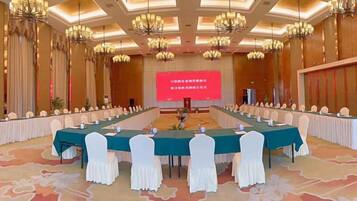 A conference room with a long table, chairs, and a screen at the front.