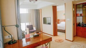 A hotel room with a wooden desk, a chair, a bed, a TV, and a bathroom with a mirror and toilet. - Lijing Hotel (Ningbo)