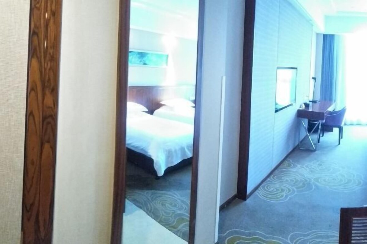 A hotel room with a bed, a desk, and a chair.