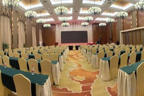 A conference room with rows of tables and chairs, a stage, and a large screen. - Lijing Hotel (Ningbo)