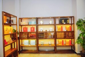 A room with a wooden bookshelf containing various items. - Lijing Hotel (Ningbo)