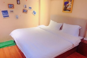 A neatly made bed with white linens in a room with a wooden floor and a green mat. - Yaocheng Hotel (Shanghai)