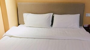 A hotel room with a bed, two pillows, and a headboard. - Yaocheng Hotel (Shanghai)