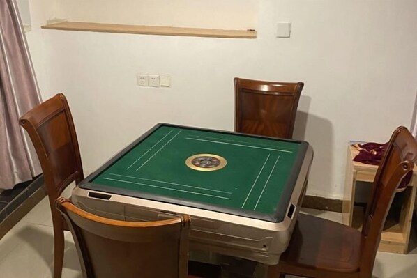 A room with a green pool table, wooden chairs, a small table with a purple cloth, and a wooden shelf above the table. - Yaocheng Hotel (Shanghai)