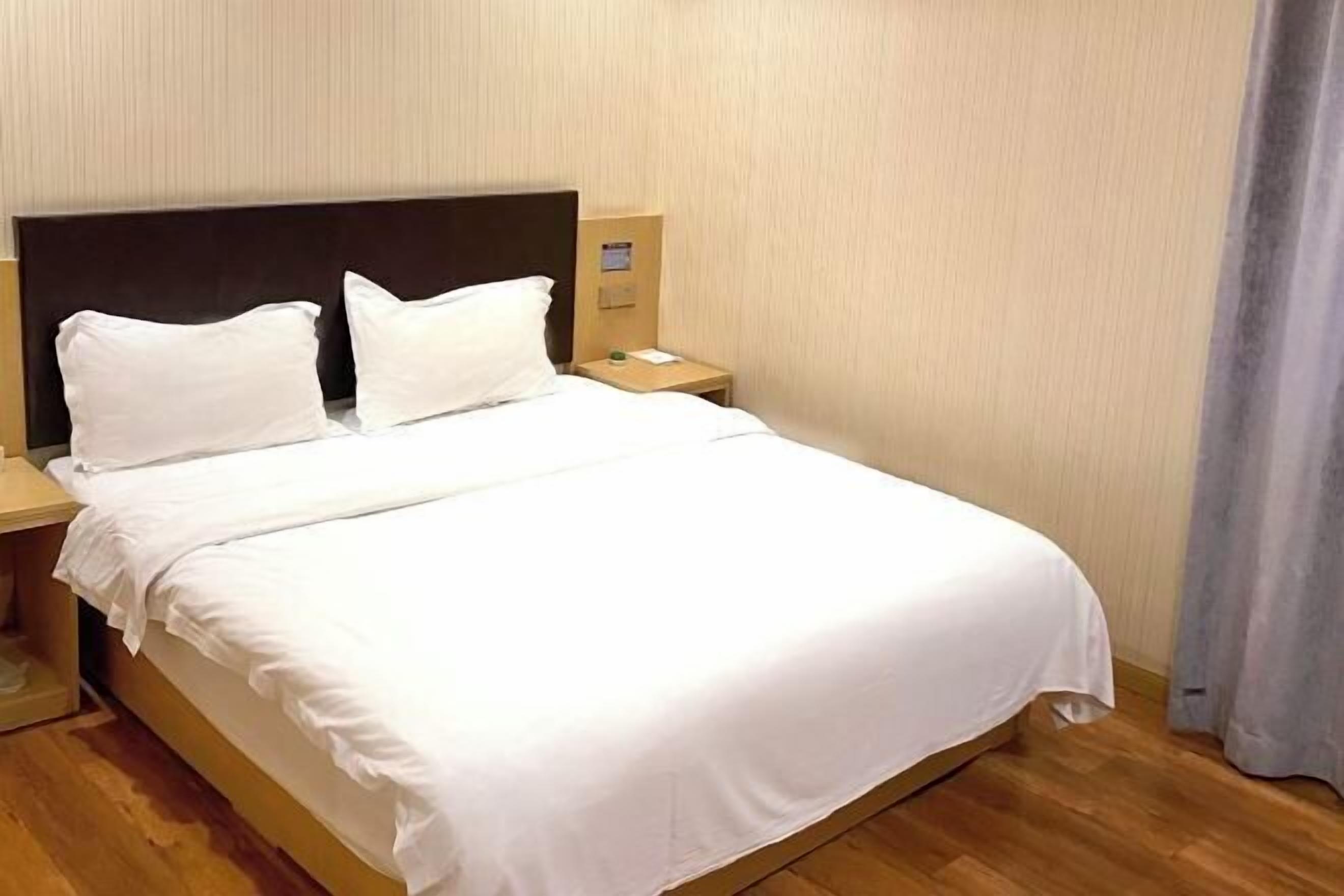 A neatly made bed with white linens in a hotel room.