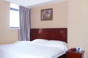 A hotel room with a bed, a nightstand, a framed picture on the wall, and a window with curtains. - Yaocheng Hotel (Shanghai)