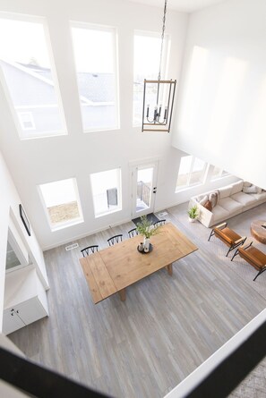 Un salón amplio con una mesa de comedor de madera, un sofá y una lámpara colgante.