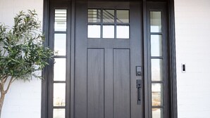 En mørkebrun hoveddør med et glaspanel, en lille postkasse og en dørmåtte med teksten "hello".