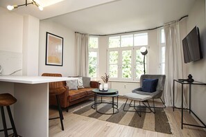 A modern living room with a sofa, armchair, coffee table, and a flat-screen TV mounted on the wall. - Close to the beach, sauna + swimming pool free of charge - Strandresidenz Brandenburg FeWo 30 - House (Göhren)