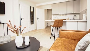 A modern kitchen with white cabinets and a black countertop. There is a dining area with a round table and two chairs. - Close to the beach, sauna + swimming pool free of charge - Strandresidenz Brandenburg FeWo 30 - House (Göhren)
