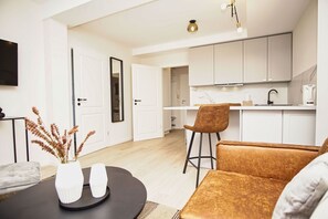 A modern kitchen with white cabinets and a black countertop. There is a dining area with a round table and two chairs. - Close to the beach, sauna + swimming pool free of charge - Strandresidenz Brandenburg FeWo 30 - House (Göhren)