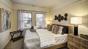 Een slaapkamer met een bed, nachtkastjes, een lamp en een decoratief wandobject.