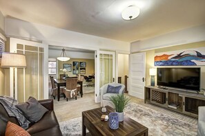 A spacious living room with a large TV, comfortable seating, and a dining area with chairs and a table. - Exceptional charming spacious 2bedroom French colonial in desirable midtown area (Sacramento)