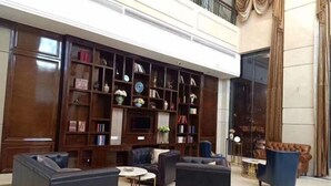 Un vestíbulo amplio con una gran estantería de madera, sofás de cuero y un televisor.