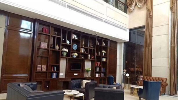A spacious lobby with a large wooden bookshelf, leather sofas, and a television. - Vienna International Hotel (Loudi Stadium) (Loudi)