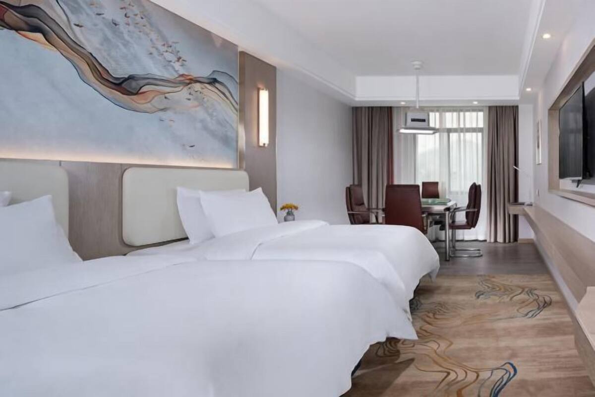 A hotel room with a large bed, a desk, and a television.