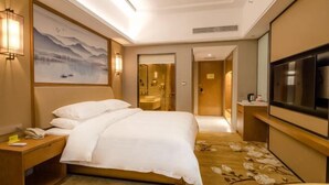 A hotel room with a bed, bedside table, lamp, artwork, and a TV. - Vienna International Hotel (Loudi Stadium) (Loudi)