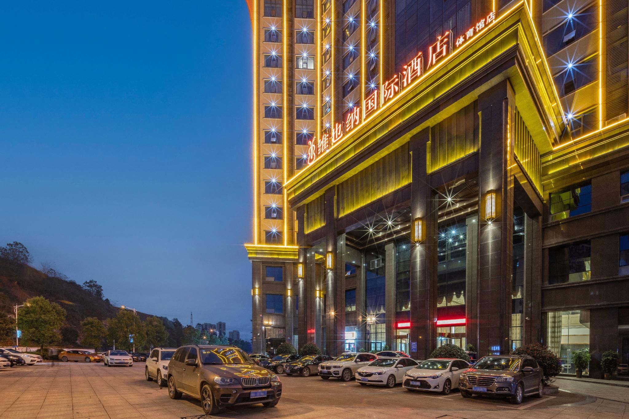 A multi-story hotel with a prominent entrance and a parking lot filled with cars.