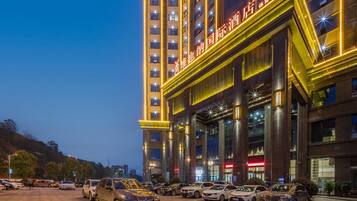 A multi-story hotel with a prominent entrance and a parking lot filled with cars.