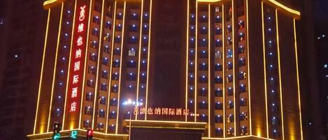 A multi-story hotel building with illuminated signage and a row of windows on each floor.