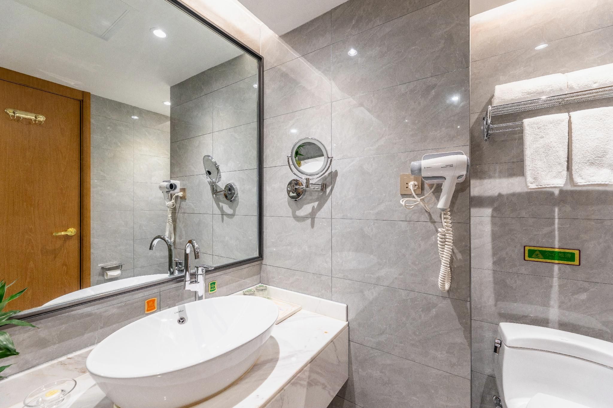 A modern bathroom with a large mirror, a hairdryer, and a sink.