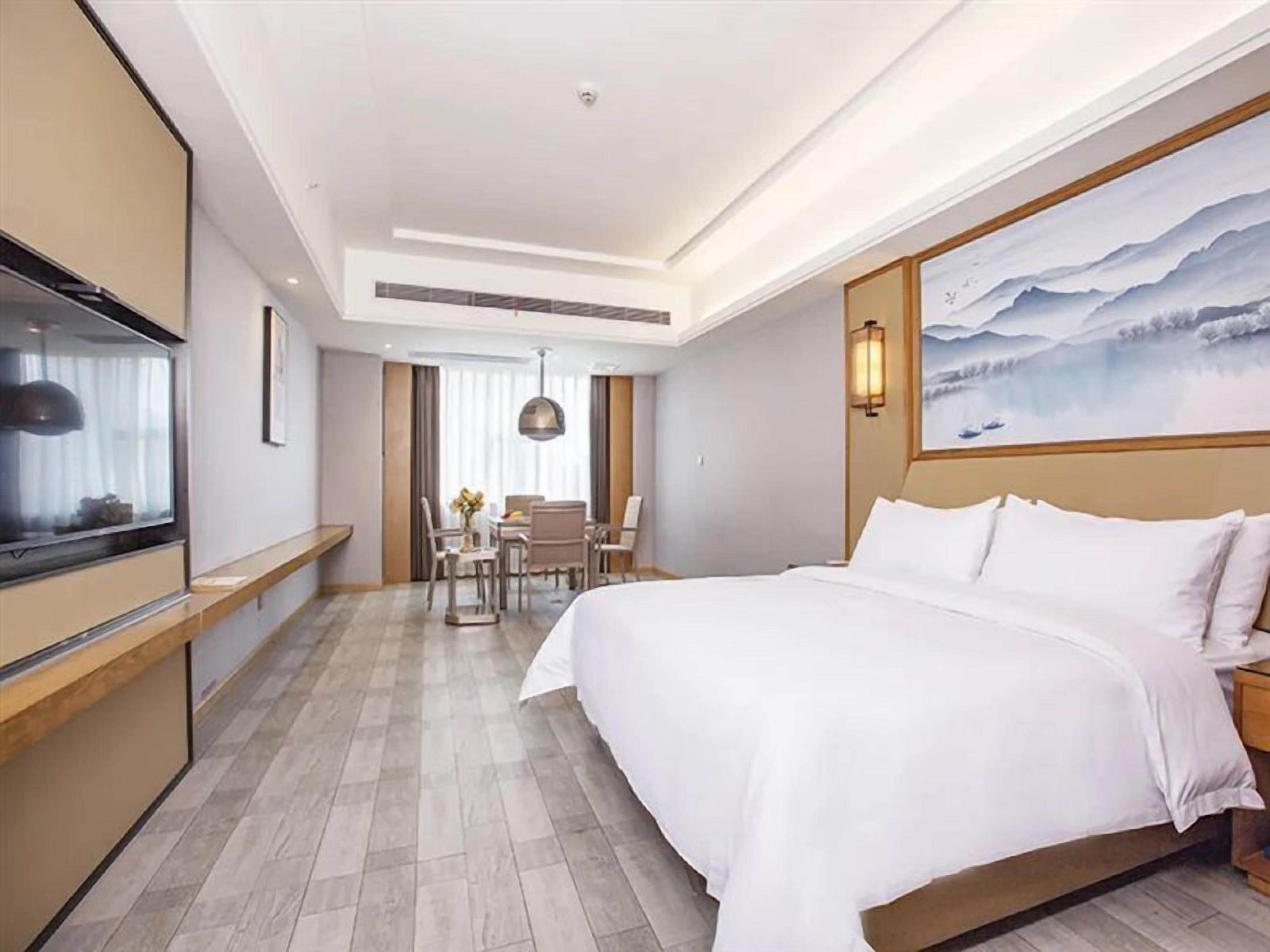 Une chambre d’hôtel avec un lit, un bureau, une chaise et un tableau au mur.