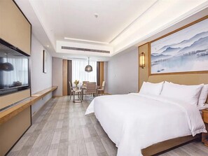 A hotel room with a bed, a desk, a chair, and a painting on the wall. - Vienna International Hotel (Loudi)