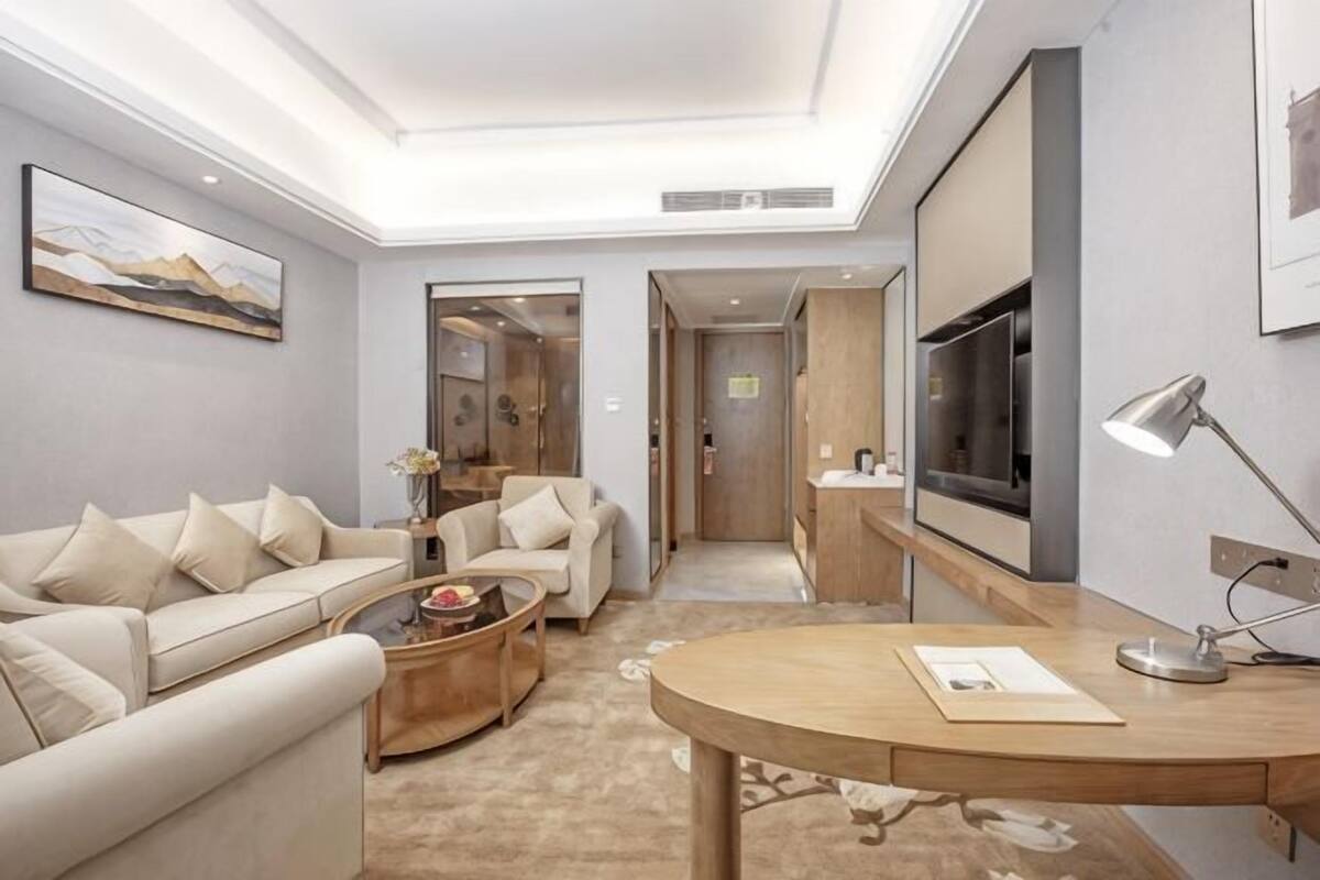 A modern living room with a sofa, coffee table, and a dining table.