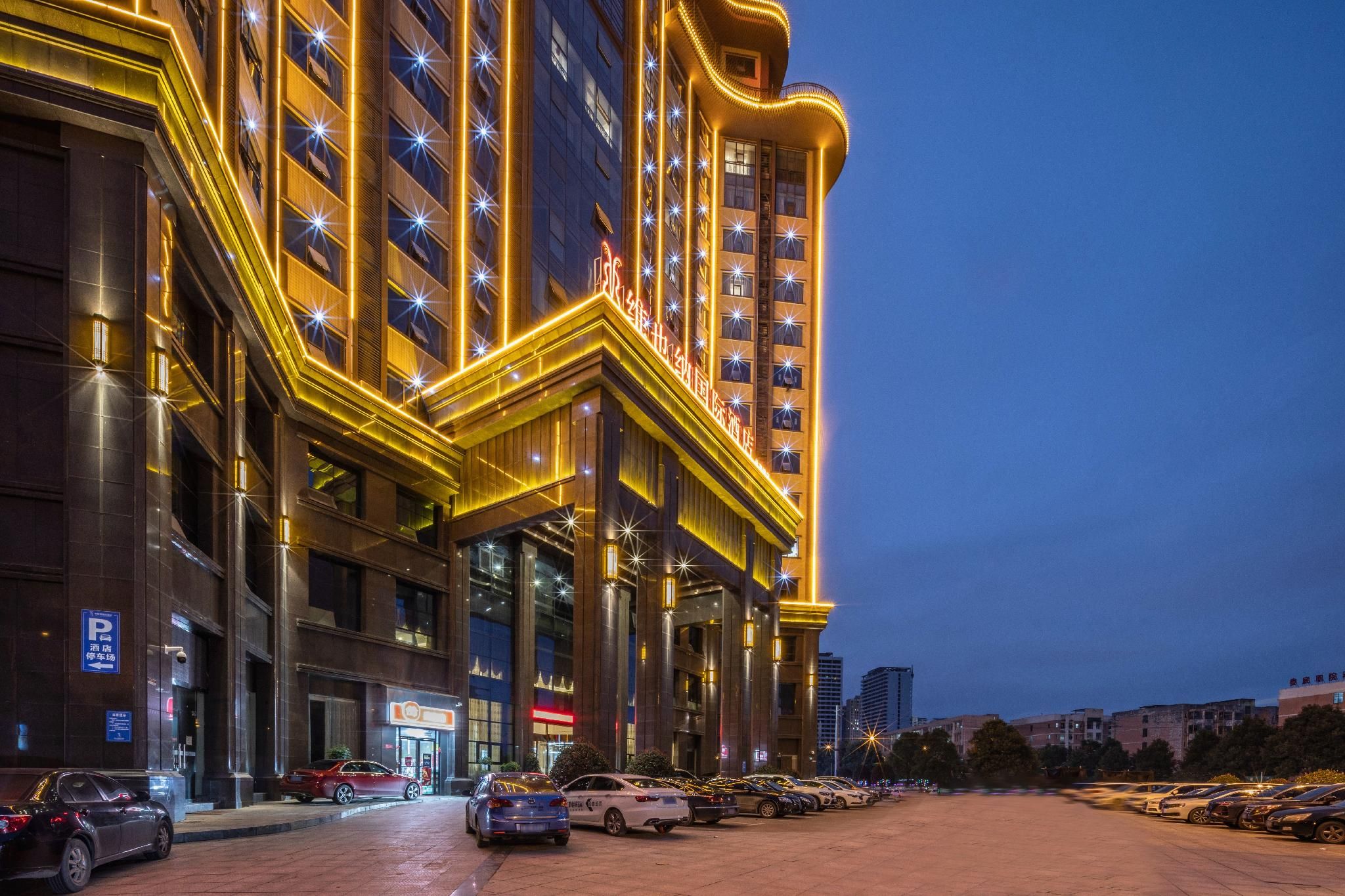 A multi-story hotel with a prominent entrance, a parking lot, and a clear view of the surrounding urban area.