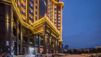 A multi-story hotel with a prominent entrance, a parking lot, and a clear view of the surrounding urban area.