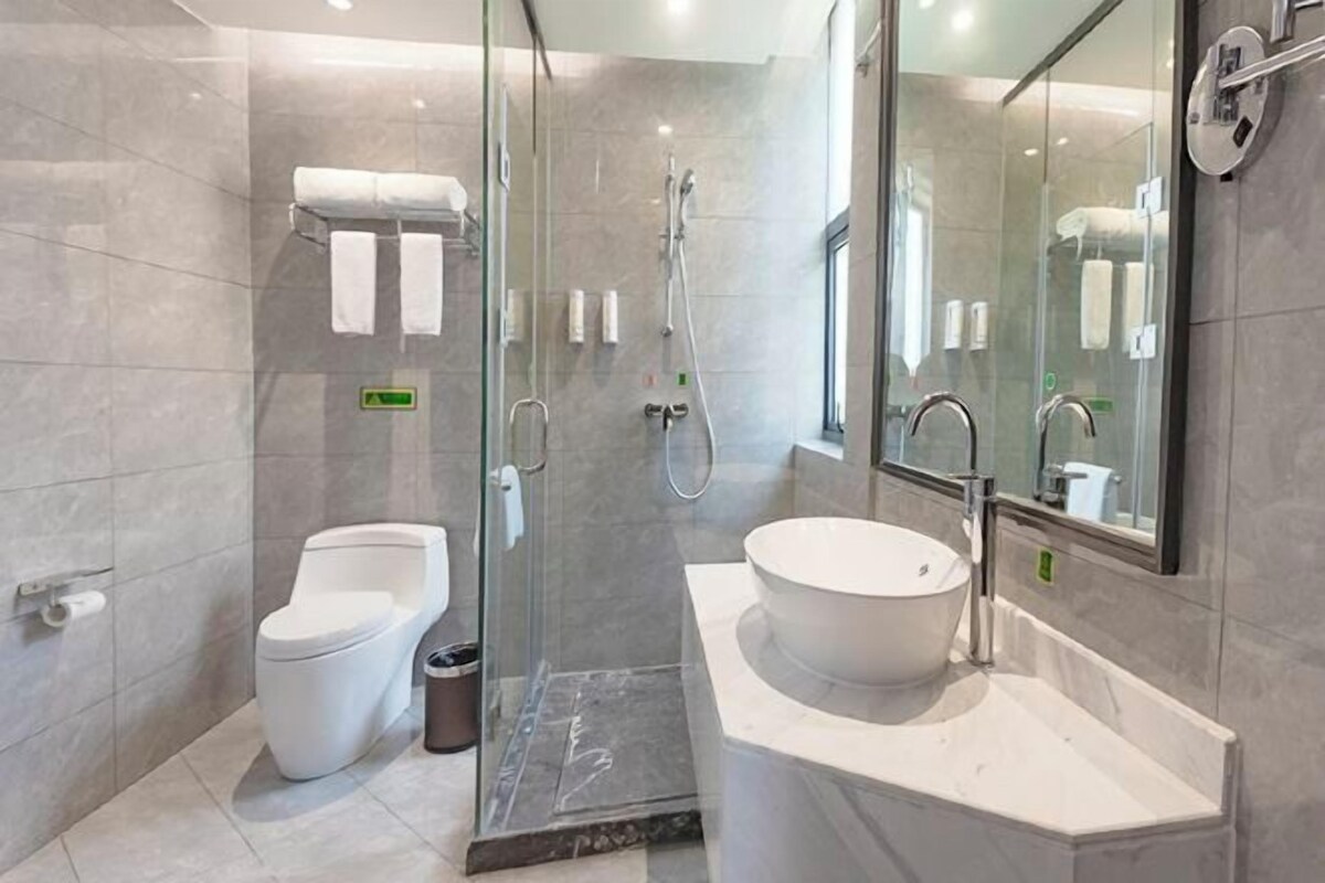 A modern bathroom with a glass-enclosed shower, a toilet, and a large sink.