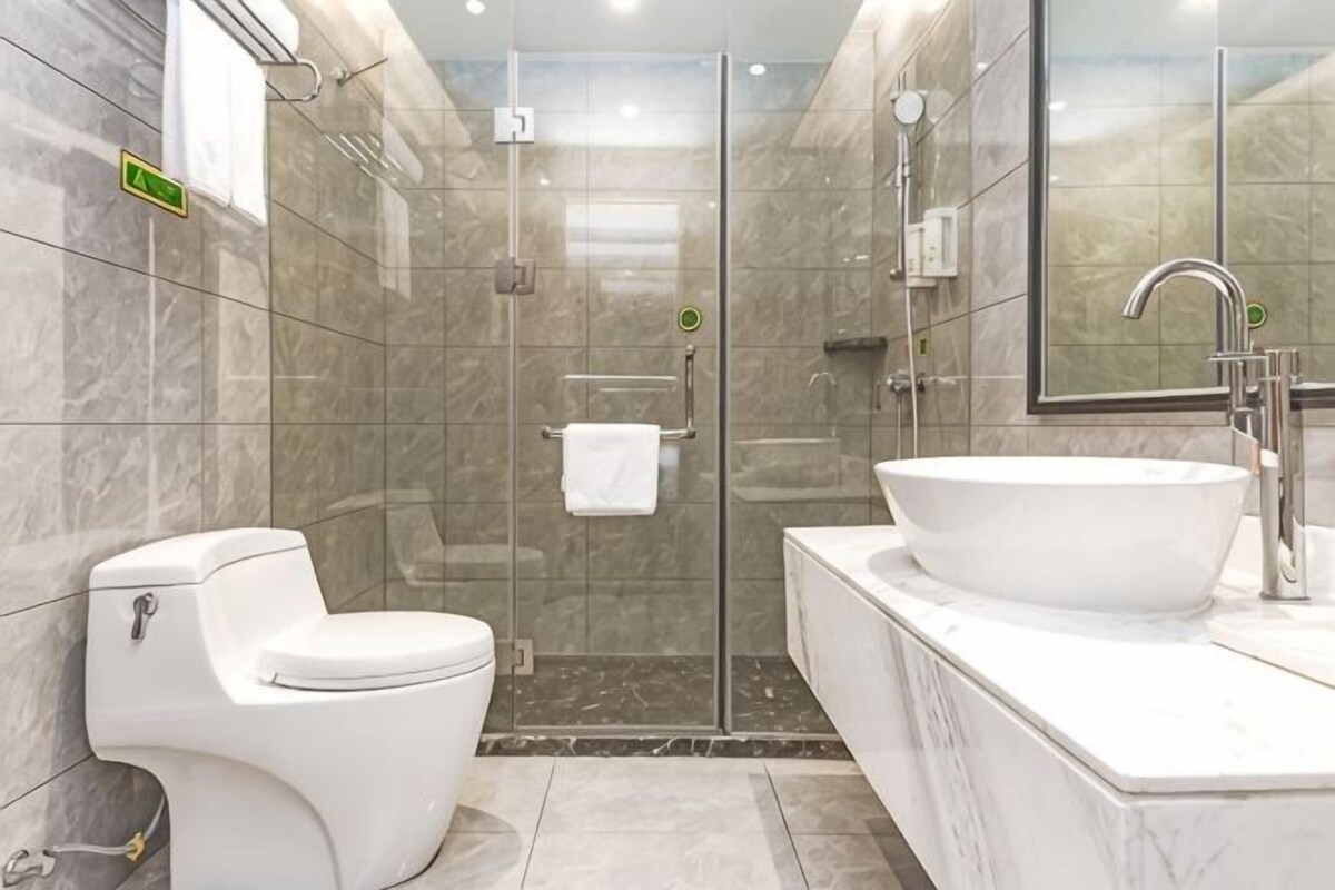 A modern bathroom with a toilet, shower, and sink.