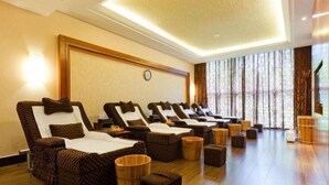 Un cuarto de spa con sillones reclinables, taburetes de madera y un ventanal con cortinas.